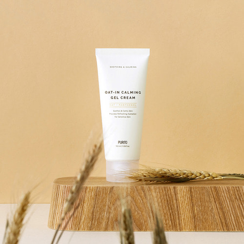 A promotional photo of the Purito oat in gel cream on a wooden slab surrounded by oat plants.